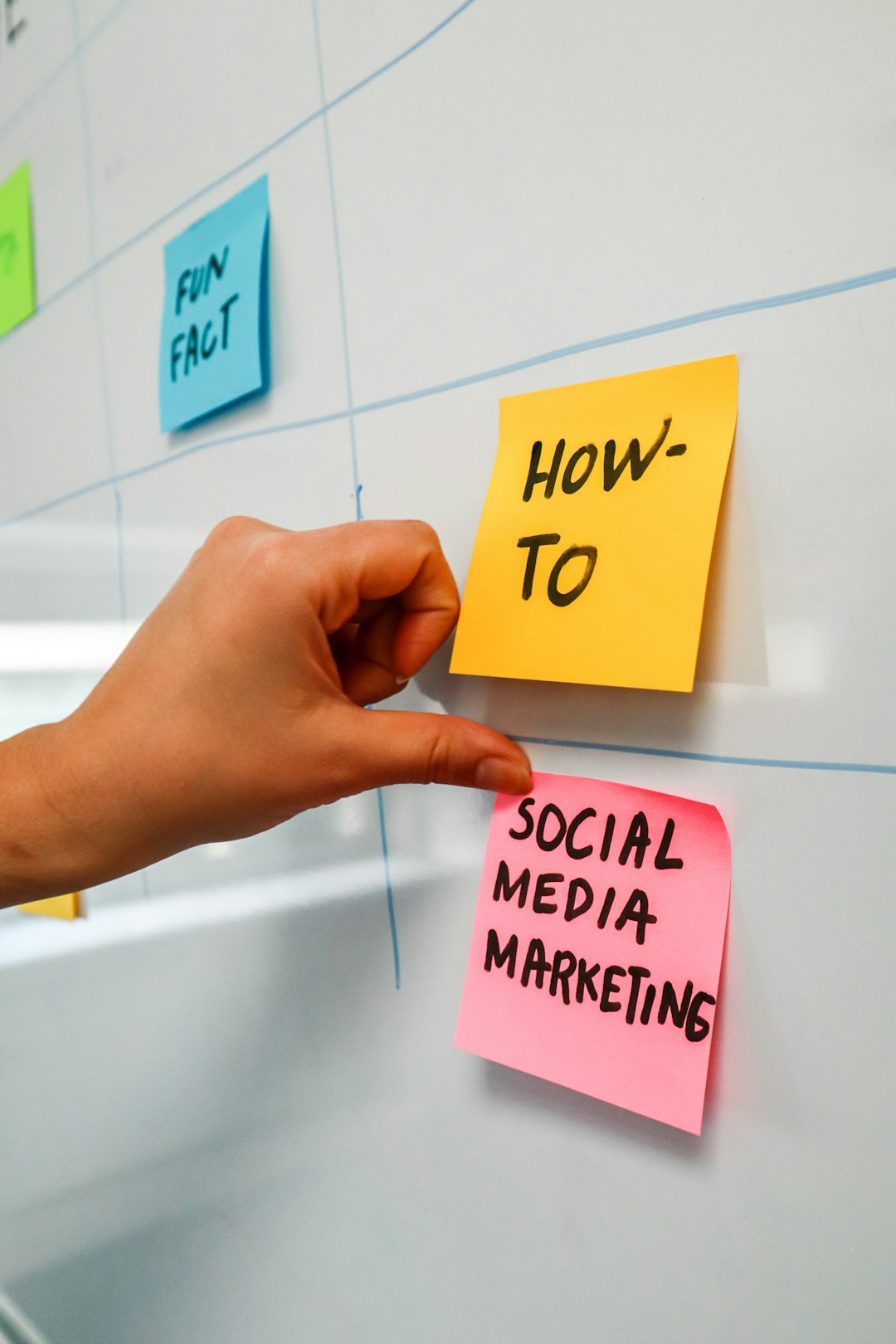 Person sticking a post-it on a white board with the words Social Media Marketing written on it